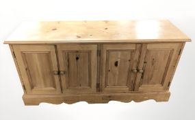 A pine four door low sideboard, 133 cm x 41 cm x 65 cm.