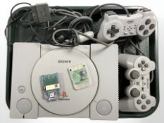 A Sony Playstation 1 console, model SCPH-9002, with two controllers and leads.