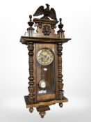 A late 19th century wall clock with pendulum, key and an eagle pediment.