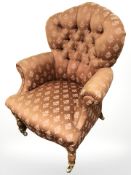 A Victorian style lady's armchair in peach upholstery, raised on brass castors, width 73 cm.