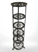 A painted cast iron six tier pan stand on paw feet, height 122 cm.