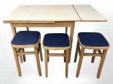 A 20th century melamine topped extending kitchen table and three stools