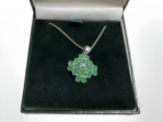 A silver pendant on chain, set with emerald coloured stones.
