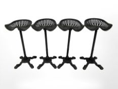 A set of four painted cast iron tractor seat bar stools.
