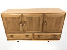 An Ercol stained elm sideboard fitted with three cupboards and pair of drawers,