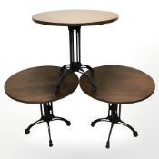 Three circular stained pine tables on painted metal supports,