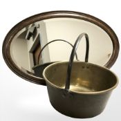 A brass jam pan and an Edwardian oak oval mirror,