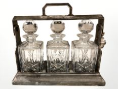 An EPNS three bottle Tantalus with three crystal decanters, width 34 cm.