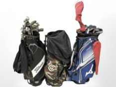 Three golf bags containing assorted irons and drivers, including Ping, Mizuno, Cleveland, etc.