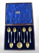 A cased set of silver gilt teaspoons, with matching tongs and straining spoon, Birmingham marks.