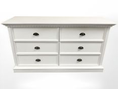 A contemporary white six drawer chest, 152 cm x 50 cm x 83 cm.