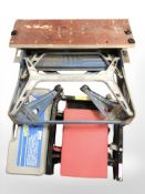 A Workmate folding bench, a boxed hydraulic roller jack and a padded inspection board on castors.
