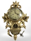 A reproduction gilded continental wall clock, length 52 cm.