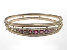 A 9ct gold antique bangle set with graduated rubies, internally 6 cm x 5 cm.