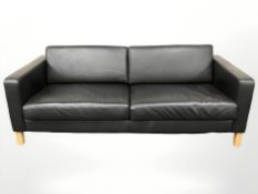 A contemporary Scandinavian black leather three seater settee on wooden legs,
