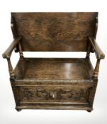 A carved oak storage monks bench, width 93 cm.