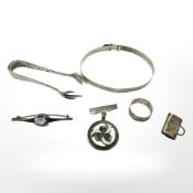 A small group of silver items to include sugar tongs, enamelled brooch, charm, brooch,