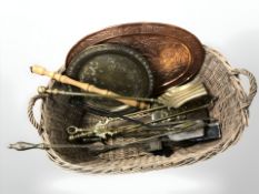 A wicker laundry basket, width 76 cm, containing assorted brass fire companion pieces, chargers,