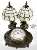 A carved oak barometer and a small pair of Tiffany-style table lamps.