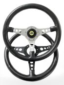 Two racing steering wheels, one with Lotus badge.
