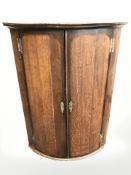 A George III oak bow front corner cabinet, height 113 cm.