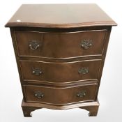 A reproduction mahogany serpentine three drawer low chest,