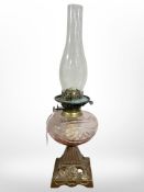 A gilt metal oil lamp with rose tinted clear glass reservoir.