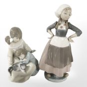 A Lladro figure of a Dutch girl, and a further figure of two sisters petting a cat, tallest 25 cm.