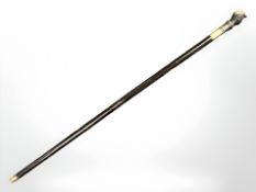 A walking cane with brass figural pommel, length 97 cm.
