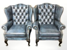 A pair of blue buttoned and studded leather Chesterfield wingback armchairs,