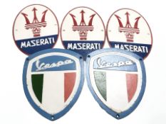 Three reproduction cast iron Maserati signs and two Vespa signs, longest 29 cm.