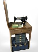 A Singer electric sewing machine in teak table, and two storage boxes.