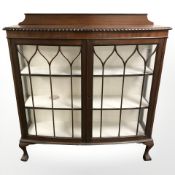 A 20th century mahogany bow-front display cabinet on claw and ball feet,