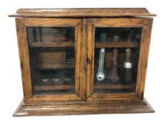 A late Victorian oak two door smokers cabinet containing three pipes, height 27 cm.