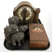 An Art Deco oak mantel clock with key, a group of carved hardwood elephants,