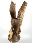 A carved wooden figure of an eagle fighting a cobra, height 77 cm.