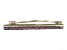 A yellow gold bar brooch channel set with rubies, length 35 mm. CONDITION REPORT: 2.