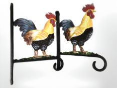 Two cast metal cockerel basket hangers.