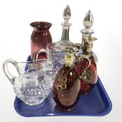 A group of crystal decanters, glass jugs, a pair of ruby tinted glass antique decanters with labels.
