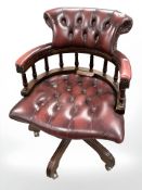 A Burgundy leather revolving buttoned captain's chair