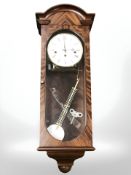 A Comitti of London wall clock with pendulum and key, length 68 cm.