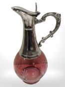 An antique cranberry glass claret jug, mounted in silver plate.