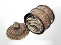 An antique copper and brass Tibetan prayer pot containing scrolls.