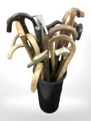 A quantity of wooden walking sticks, a climbing axe, umbrella, etc.