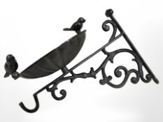 A cast iron bird bath on bracket.