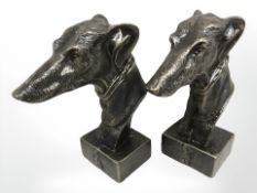 A pair of cast greyhound head figures.