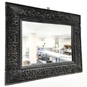 An Anglo-Indian heavily carved wall mirror, 79 cm x 64 cm.