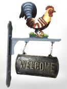 A cast cockerel welcome sign on bracket.