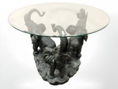 An ornate lamp table on elephant three way support with glass top, diameter 80 cm.
