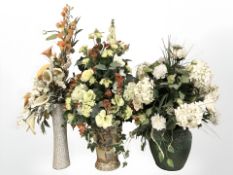 Three contemporary vases containing artificial flowers.